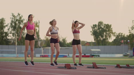 Three-female-athletes-simultaneously-start-running-marathon-rivalry-slow-motion.-women-standing-on-a-starting-line-before-race